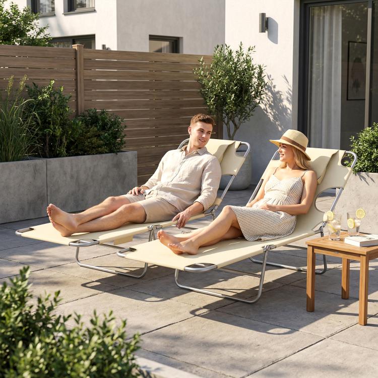 Two beige tanning chaise lounges with face pillows, reclining on an outdoor patio