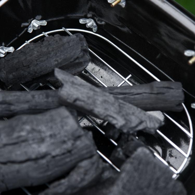 Close-up of charcoal bed inside a portable black charcoal grill cooking chamber