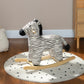Plush zebra rocking horse on a round dotted play mat with curved wooden rocker