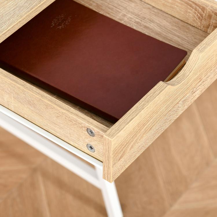 Wood drawer with dark interior panel and round metal pulls on natural desk