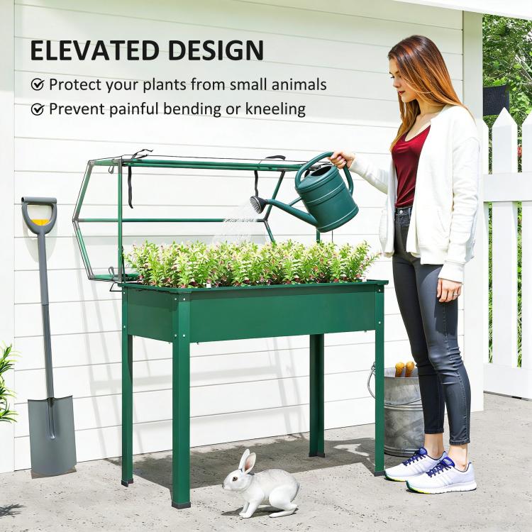 Green elevated garden bed with clear flip-up greenhouse cover and plant watering