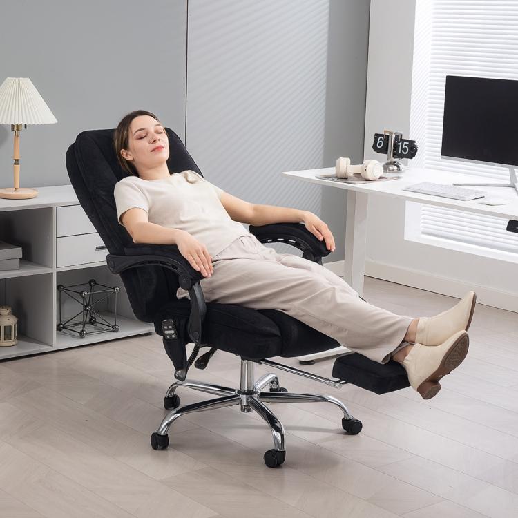 Black reclining massage office chair with footrest, shown in use in a home office.