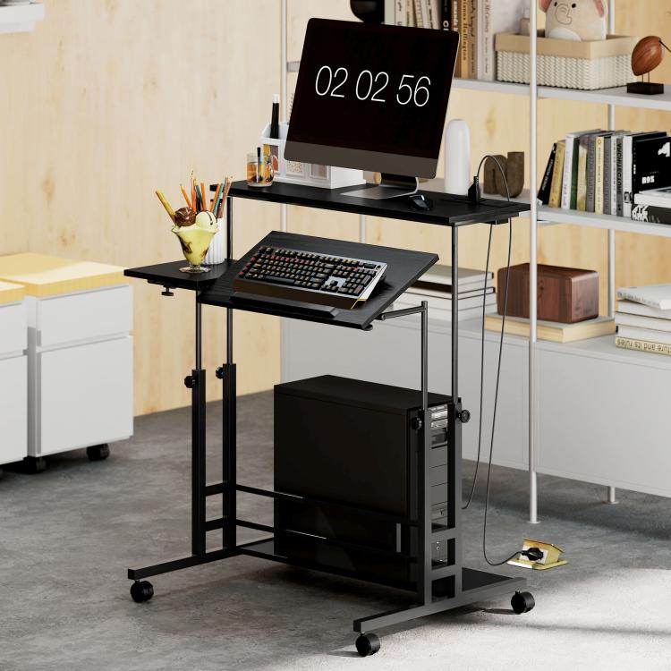 Black standing desk with monitor setup, tilting keyboard tray, and enclosed lower storage.
