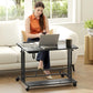Black mobile standing desk with tilting tabletop, keyboard tray, under-shelf, and caster wheels.