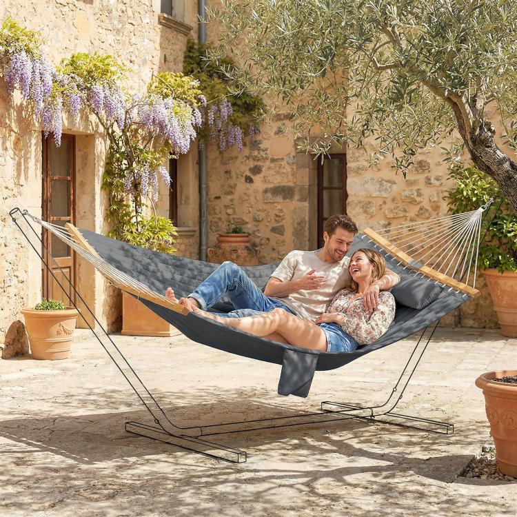 Two-person gray outdoor hammock with pillow, draped fabric and wooden spreader bars