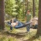 Gray outdoor hammock for two with pillow, suspended between trees with wooden spreader bars