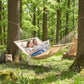 Cream hammock hanging from trees with attached pillow for two-person lounging