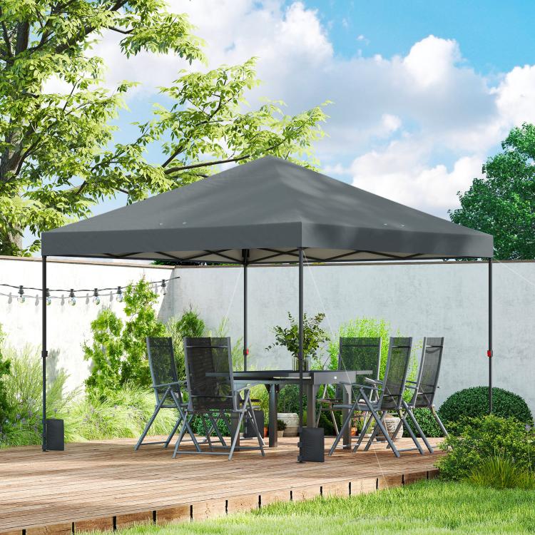 Dark gray pop-up canopy tent over outdoor deck with chairs and table underneath