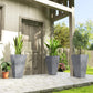 Set of 3 tall gray tapered plastic planters with plants on patio paving