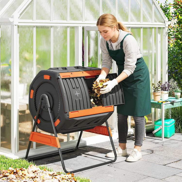 Outdoor compost tumbler on stand, open black drum with orange trim and interior food waste