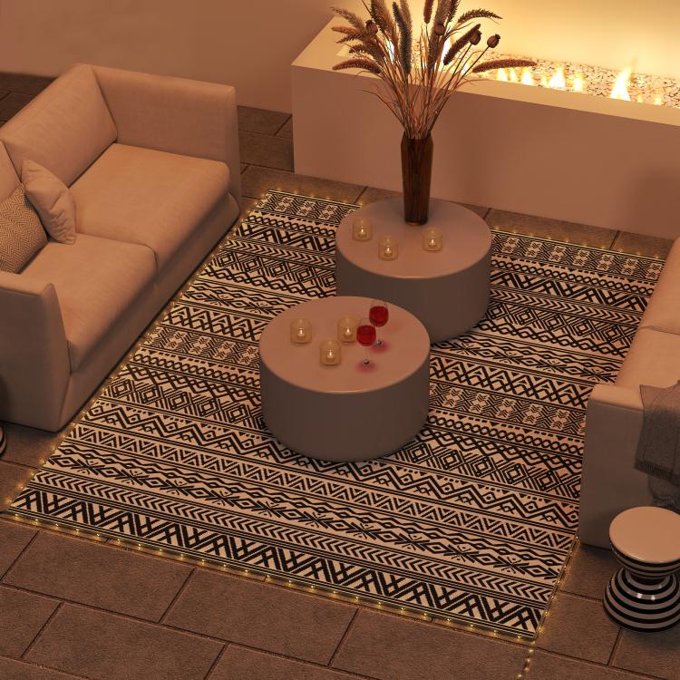 Outdoor patio rug with black-and-white geometric pattern laid on the floor.