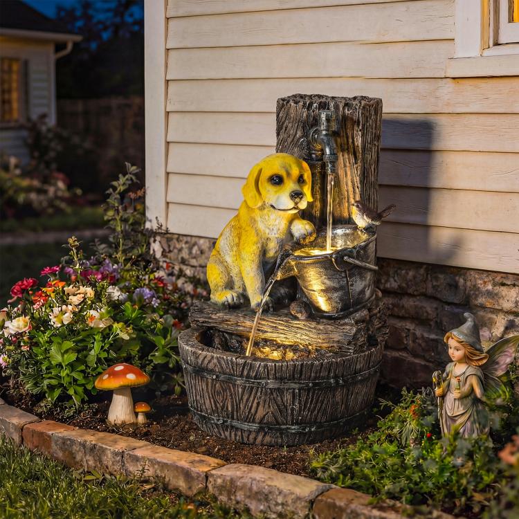 Yellow puppy statue on a three-tier rustic resin fountain in a garden display.