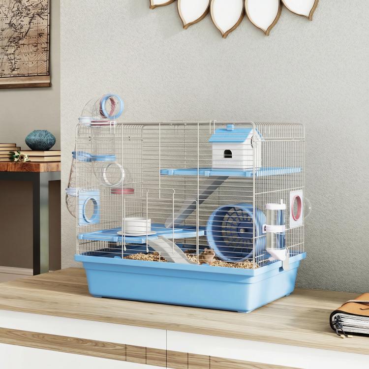 Blue hamster cage on wooden floor with ramps, house hut, wheel, and hanging water bottle