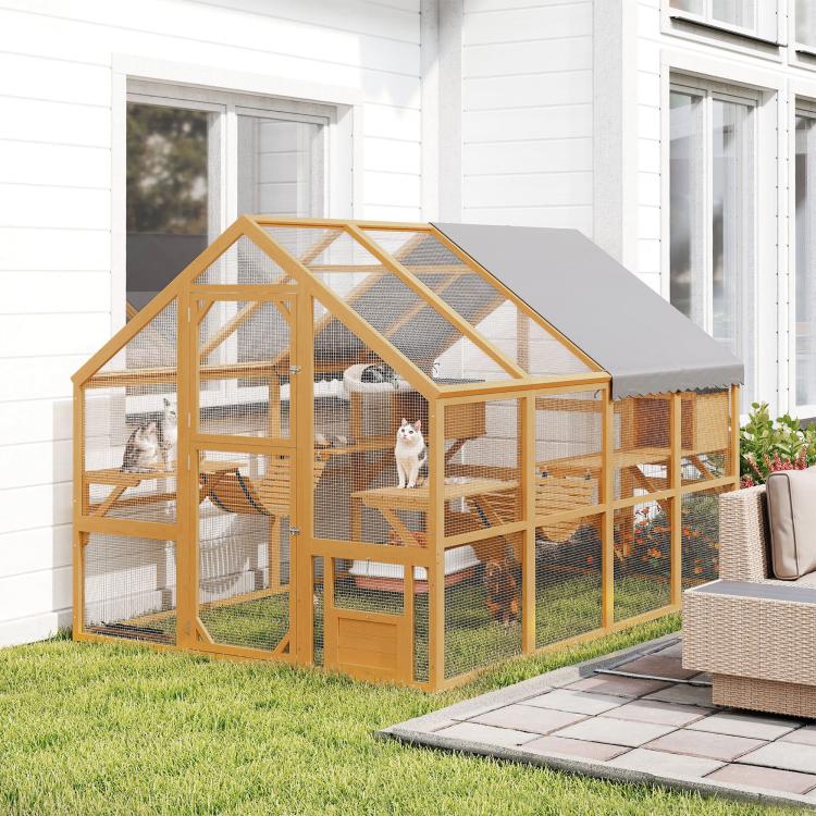 Outdoor wooden cat house with gray canopy, wire mesh enclosure, ramps, and resting areas