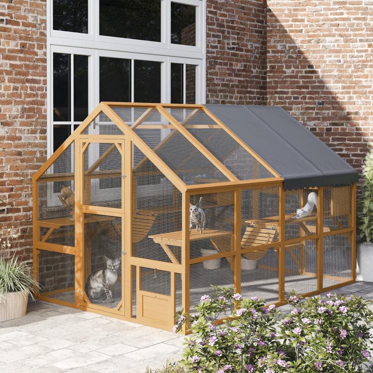 Outdoor wooden cat enclosure with gray canopy, wire mesh panels, and multiple levels