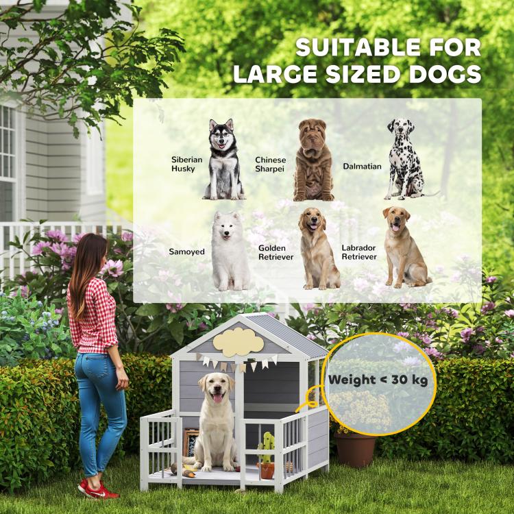 Large outdoor dog house with porch, gray siding, white railings, and dark roof.