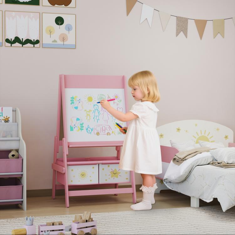 Pink kids art easel with whiteboard, double panels and storage bins; child drawing.