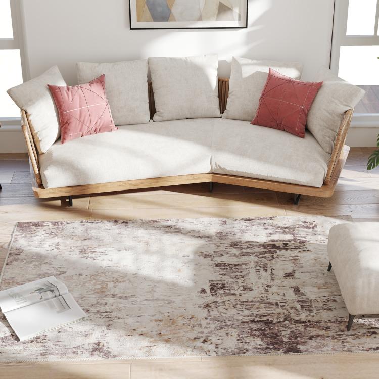 Abstract area rug beneath sofa, light background with brown distressed pattern