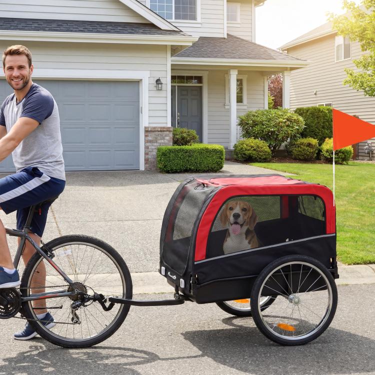 Red-and-black dog bike trailer with mesh door and four wheels, dog inside