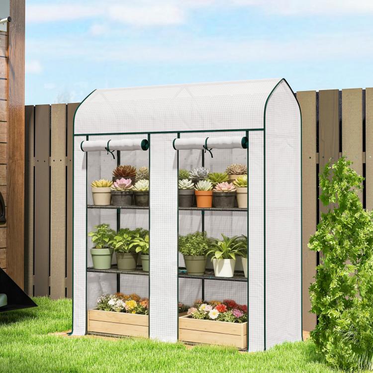 Small 3-tier mini greenhouse standing outdoors with two roll-up doors and multi-level wire racks