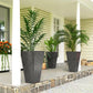 Tall black marble-finish planters with green plants on outdoor stone patio