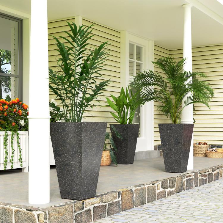 Tall black marble-finish planters with green plants on outdoor stone patio