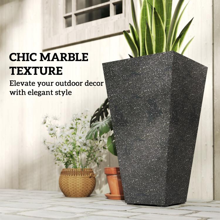 Single tall black marble-texture plastic planter with green plant and nearby flowers