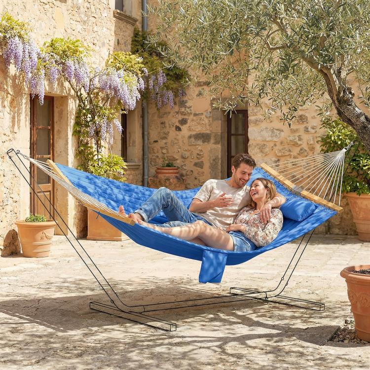 Two people relaxing in a blue two-person hammock with built-in pillow
