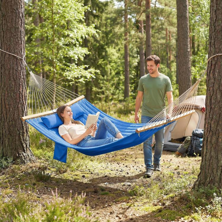 Blue two-person hammock with wooden spreader bars, two people reading outdoors