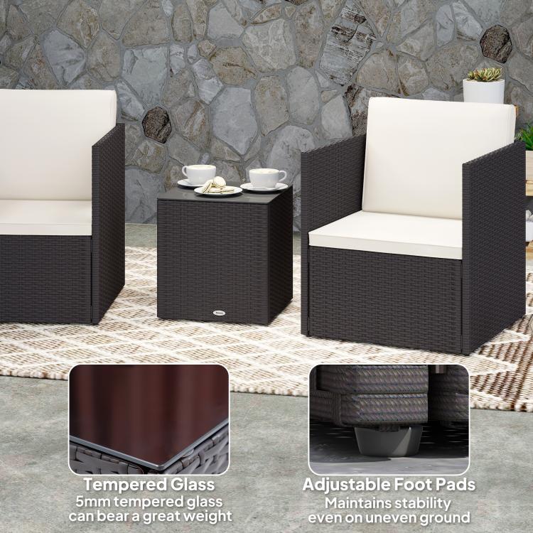 Wicker bistro set with glass-top square table and two armchairs, cream cushions