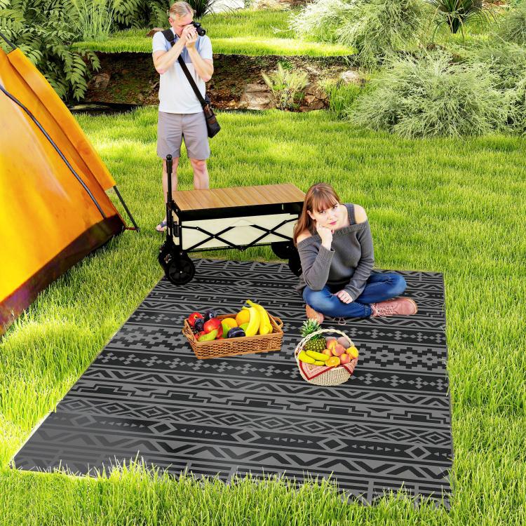 Black and gray outdoor rug with geometric pattern under a picnic setup on grass