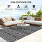 Outdoor rug with black and gray geometric pattern beneath outdoor seating on patio