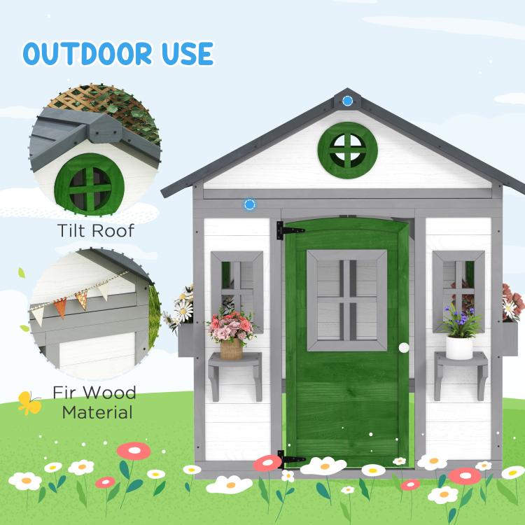 White wooden outdoor playhouse with dark roof, green door, and window shutters