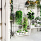 White metal vertical plant trellis with hanging chain and bottom shelf with potted greenery
