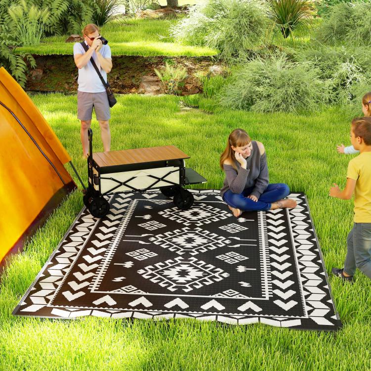 Outdoor reversible rug spread on grass with bold black and white geometric print
