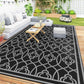Outdoor rug with black background, gray quatrefoil pattern, and dark border
