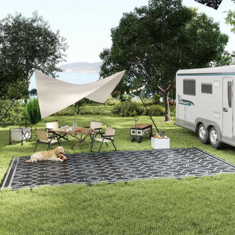 Outdoor reversible rug with gray quatrefoil pattern and dark border on lawn