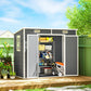 Gray plastic storage shed with wide open doors and shelves holding yard equipment