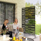 Black metal privacy screen with rectangular cutout pattern, freestanding on legs