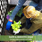 Hands planting in black raised garden bed planter with tall trellis