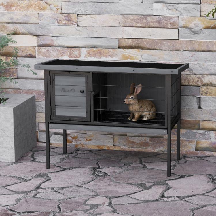 Gray elevated wooden rabbit hutch with wire enclosure and door, rabbit inside