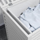 White slatted bamboo laundry hamper with inner liner bag, filled with folded clothes
