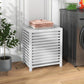 White slatted bamboo laundry hamper with lid holding folded towels