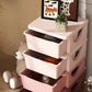Pink kids dresser tower with three drawers open, stacked on a raised base