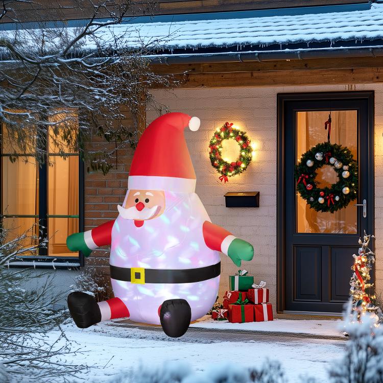 Inflatable Santa decoration standing on snow near front door wreath and gift boxes