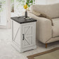 White distressed end table with black top next to sofa, featuring a front storage door