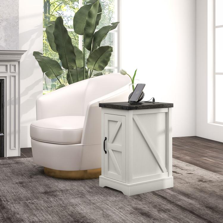 White side table with black top and storage door, holding a phone charging on top