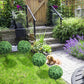 Artificial boxwood ball topiary trees with green foliage and ground stakes in yard landscaping