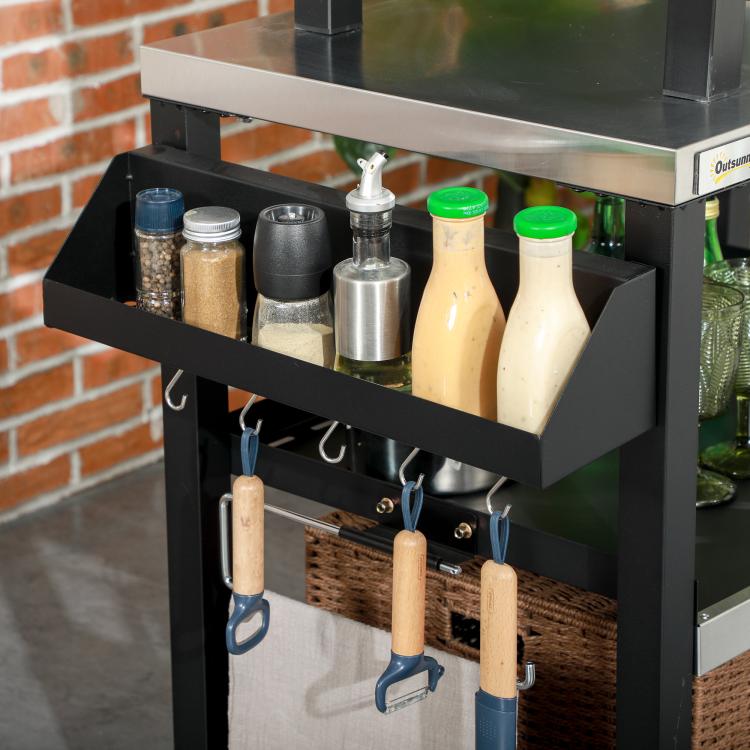 Side shelf on black grill cart holding spice bottles and metal tools, with hooks