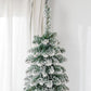 Snow-frosted artificial Christmas tree with dense green needles and snowy tips
